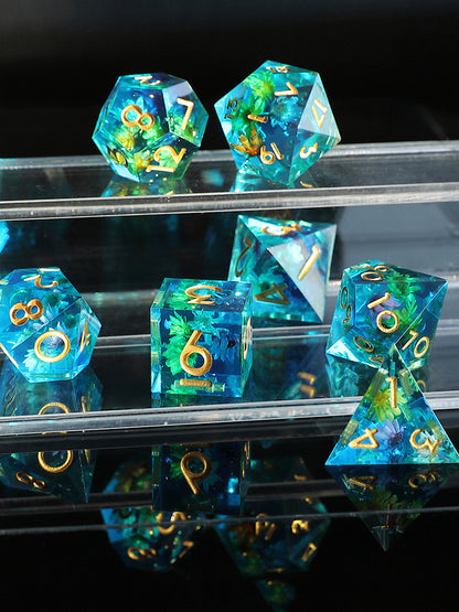 Set of blue and green dice with gold numbers on a reflective surface
